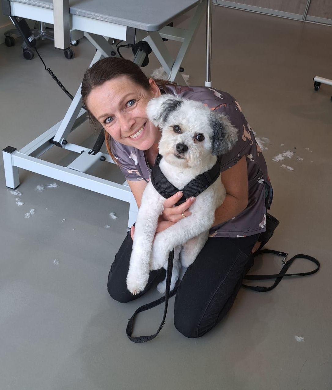 Aukje zit op de vloer van de salon en knuffelt een klein wit hondje